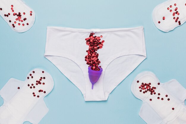 Bovenaanzicht knickers met rode pailletten en menstruatie cup