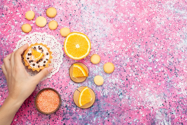 Bovenaanzicht koekjes en cake met stukjes sinaasappel op het gekleurde oppervlak koekjeskoekje fruitcake suiker zoet