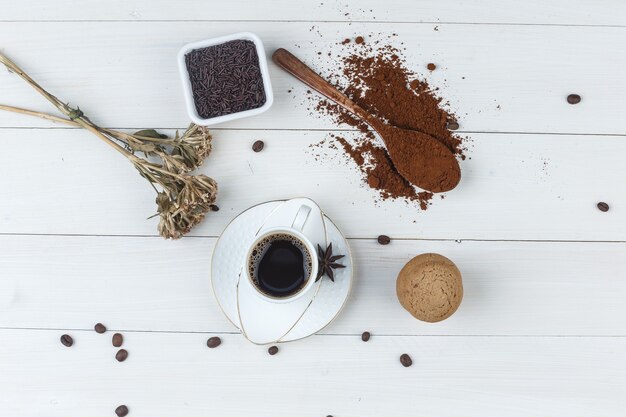 Bovenaanzicht koffie in beker met gemalen koffie, koffiebonen, gedroogde kruiden, specerijen