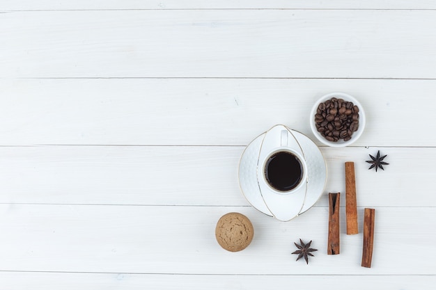 Bovenaanzicht koffie in beker met koffiebonen, kruiden, koekje op houten achtergrond. horizontaal
