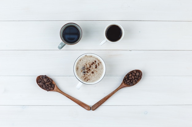 Bovenaanzicht koffie in kopjes met koffiebonen op houten achtergrond. horizontaal