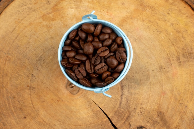 bovenaanzicht koffie zaden bruin binnen blauwe pot op het houten bureau