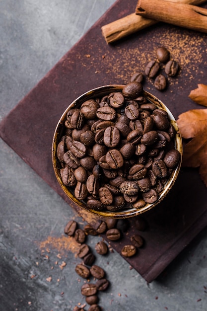 Bovenaanzicht koffiebonen in beker op snijplank met kaneel