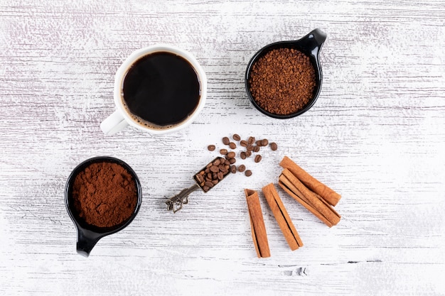 Bovenaanzicht koffiekopje met instant koffie en kaneel op witte tafel