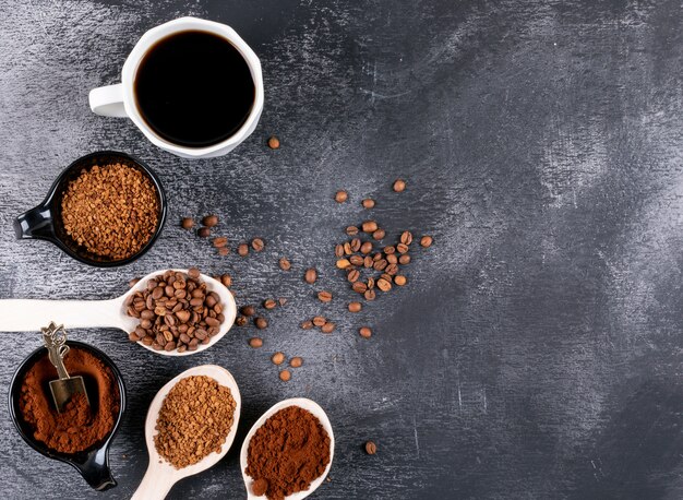 Bovenaanzicht koffiekopje met koffiebonen en oploskoffie op donkere tafel