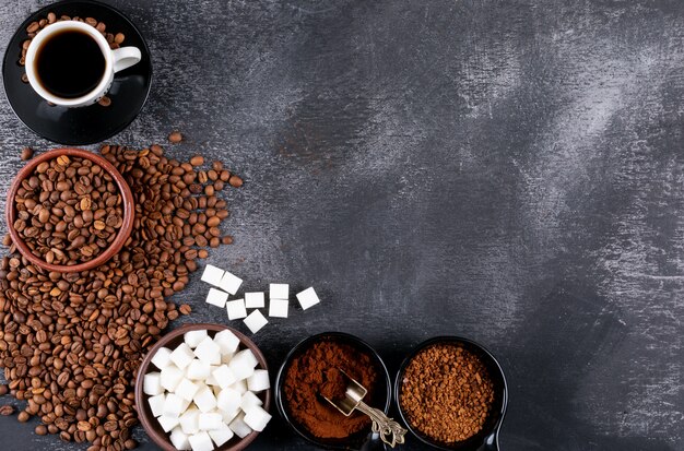 Bovenaanzicht koffiekopje met koffiebonen en suikerklontjes op donkere tafel