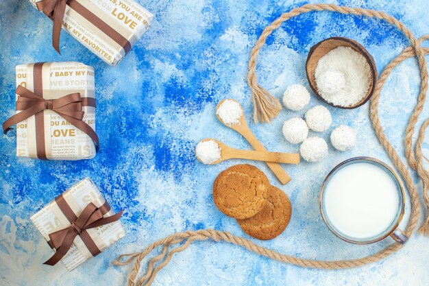 Bovenaanzicht kokos ballen touw houten lepels kopje melk cookies op blauw witte achtergrond