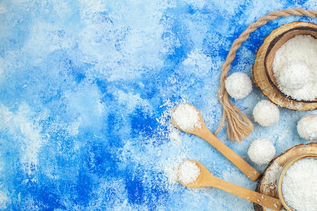 Bovenaanzicht kokospoeder kommen op houten bord kokos sneeuwballen touw houten lepels op blauw witte achtergrond met vrije plaats