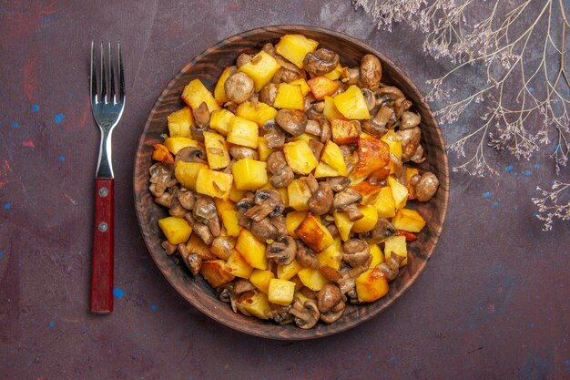 Bovenaanzicht kom met eten en vork een vork en een bord met aardappelen en champignons staan op tafel