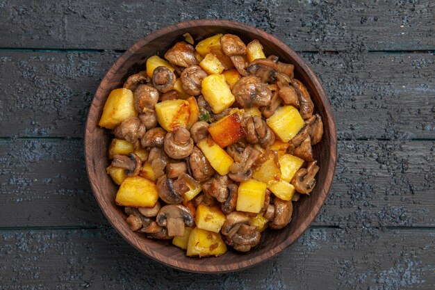 Bovenaanzicht kom met voerbak met aardappelen en champignons op de grijze tafel