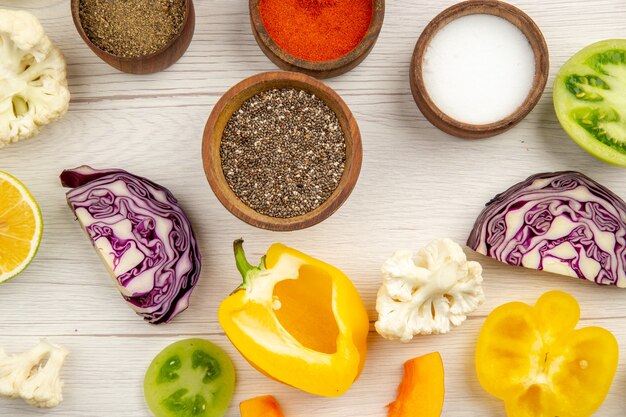 Bovenaanzicht kommen met kruiden gesneden paprika bloemkool gesneden rode kool gesneden groene tomaten op witte tafel