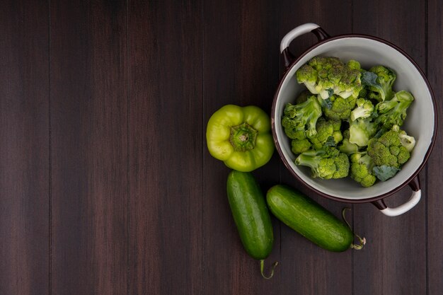 Bovenaanzicht kopie ruimte broccoli in een pan met komkommers en paprika's op houten achtergrond