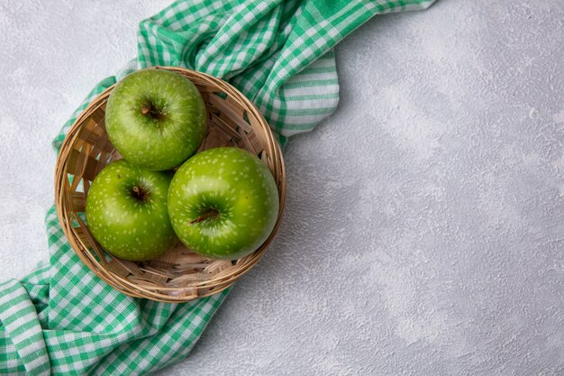 Bovenaanzicht kopie ruimte groene appels in mand op groene geruite handdoek op witte achtergrond