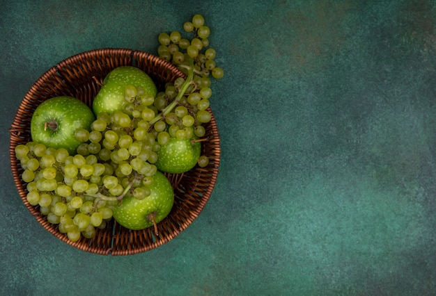 Bovenaanzicht kopie ruimte groene druiven met appels in een mand op een groene achtergrond