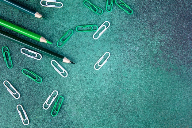 Bovenaanzicht kopie ruimte groene potloden met groene en witte paperclips op een groene achtergrond