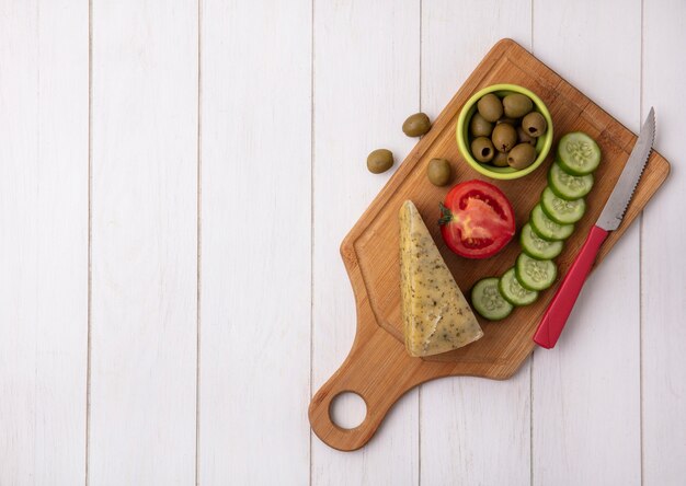 Bovenaanzicht kopie ruimte kaas met tomaten, komkommer en olijven met mes op standaard op witte achtergrond