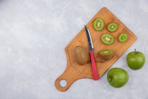 Bovenaanzicht kopie ruimte kiwiplakken met mes op snijplank met groene appels op witte achtergrond