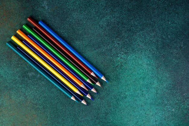 Bovenaanzicht kopie ruimte kleurrijke potloden op een groene achtergrond