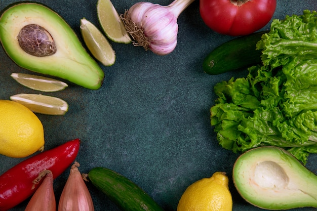 Bovenaanzicht kopie ruimte mix van groenten, avocado, citroen, tomaat, komkommers en sla op een donkergroene achtergrond