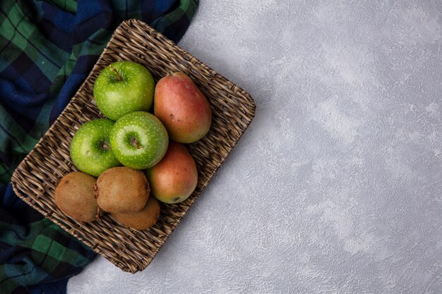 Bovenaanzicht kopie ruimte peren met groene appels en kiwi op een stand met geruite handdoeken op een witte achtergrond