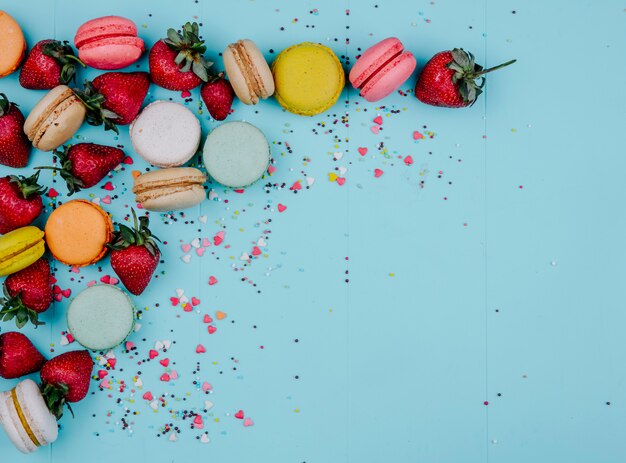 Bovenaanzicht kopie ruimte veelkleurige macarons met aardbeien op een blauwe achtergrond