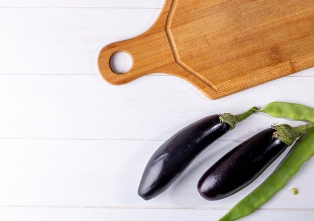 Bovenaanzicht kopie ruimte verse aubergine met groene lobby en snijplank op een witte achtergrond