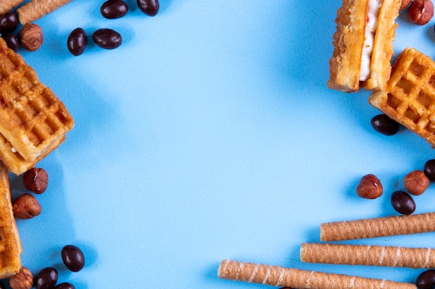 Bovenaanzicht kopie ruimte wafels met zoete buizen chocolade snoepjes en noten op blauw