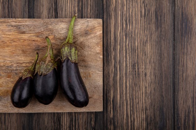 Bovenaanzicht kopie ruimte zwarte aubergine op snijplank op houten achtergrond