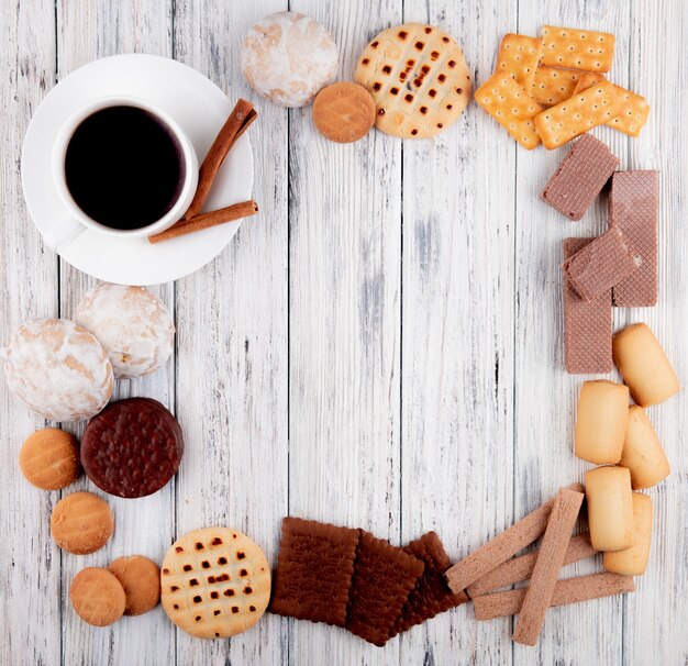 bovenaanzicht Kopje koffie met chocolade koekje knapperige wafels vanille koekjes kaneel crackers koekjes met jam op houten achtergrond