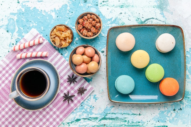 Bovenaanzicht kopje koffie met franse macarons rozijnen en confitures op lichtblauwe ondergrond cake bakken zoete suikertaart biscuit