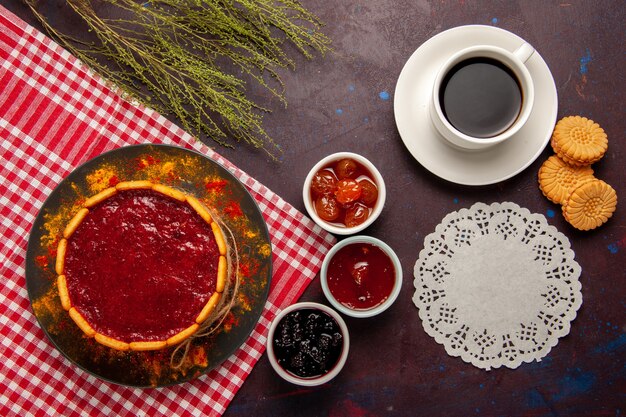 Bovenaanzicht kopje koffie met heerlijke dessertcake koekjes en fruitjams op donkere ondergrond zoet fruit koekjeskoekje zoet