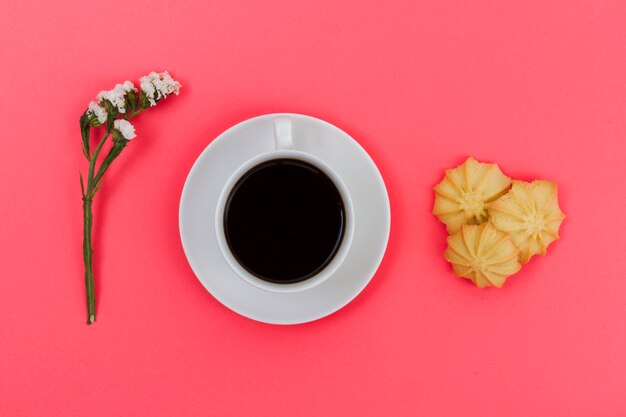 Bovenaanzicht kopje koffie met koekjes en bloem
