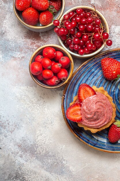 Bovenaanzicht kopje koffie met romige cake en fruit op de lichte tafel zoete koektaart