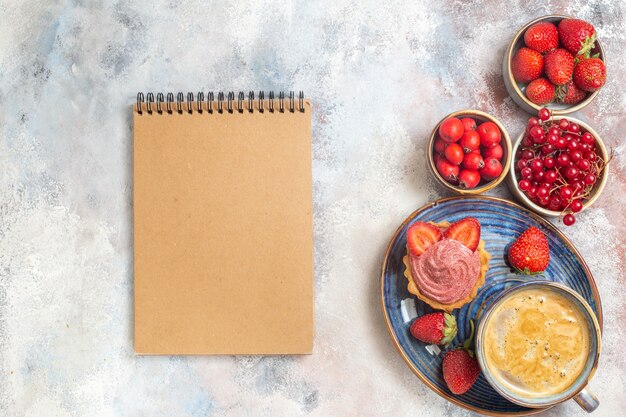 Bovenaanzicht kopje koffie met romige cake en fruit op de lichte tafel zoete koektaart