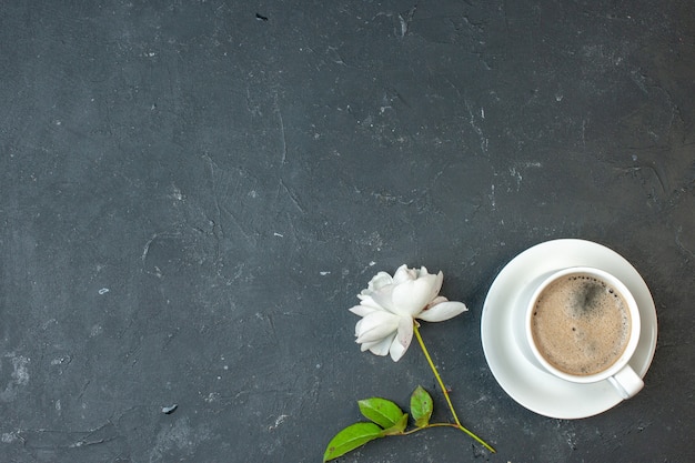 Bovenaanzicht kopje koffie met witte bloem op donkere tafel