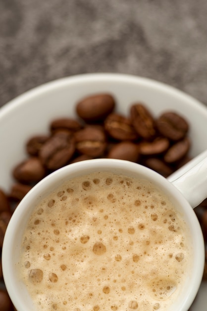 Bovenaanzicht kopje melk koffie met geroosterde bonen