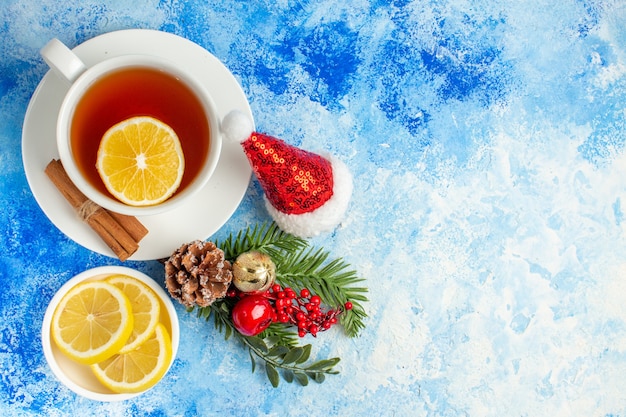 Bovenaanzicht kopje thee citroen schijfjes kerstmuts op blauwe tafel vrije ruimte