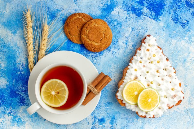 Bovenaanzicht kopje thee kerstboom cake op blauwe tafel