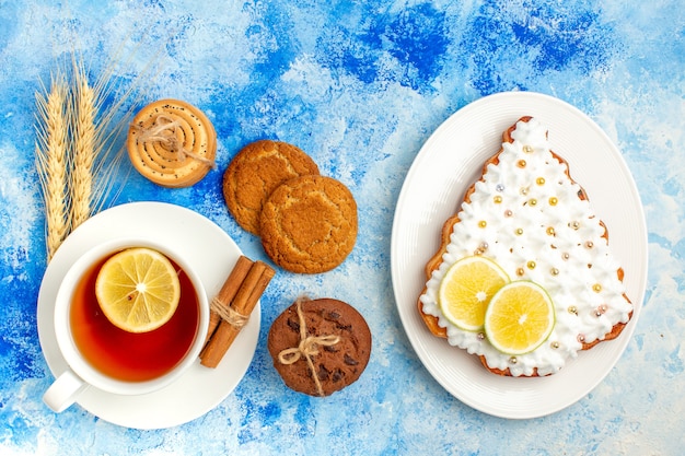 Bovenaanzicht kopje thee koekjes taart op plaat op blauwe tafel