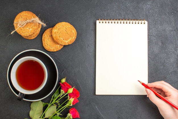 Bovenaanzicht kopje thee met bloemen en koekjes op een donkere achtergrondkleur geschenk liefdespaar gevoel huwelijk