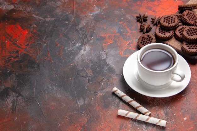 Bovenaanzicht kopje thee met choco cookies op donkere tafel biscuit theekoekjes