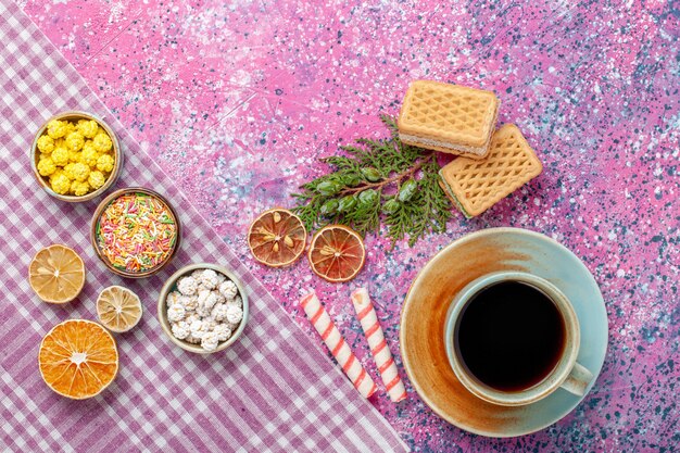 Bovenaanzicht kopje thee met crackers wafels en snoepjes op roze bureau