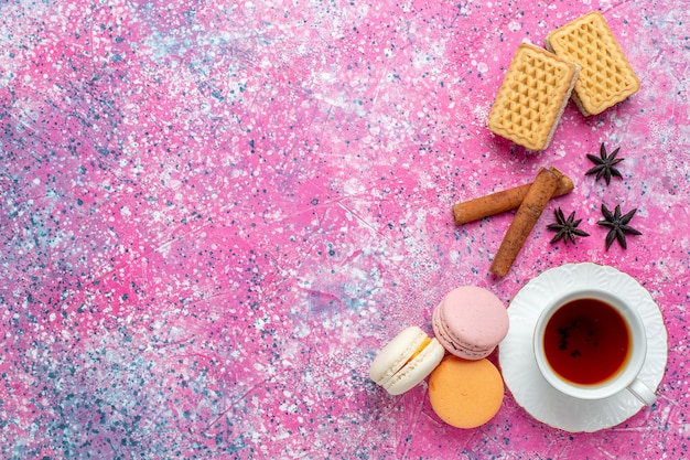 Bovenaanzicht kopje thee met Franse macarons en crackers op het lichtroze bureau