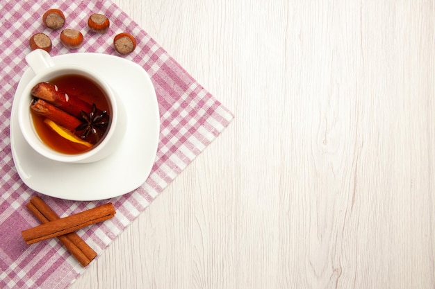 Bovenaanzicht kopje thee met hazelnoten en kaneel op wit bureau thee noot snack ceremonie walnoot