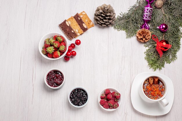 Gratis foto bovenaanzicht kopje thee met jam cake plakjes en fruit op witte tafel fruit thee gelei kleur cookie