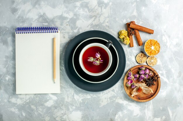 Bovenaanzicht kopje thee met kaneel en bloemen op witte bureau thee zoete drank bloem