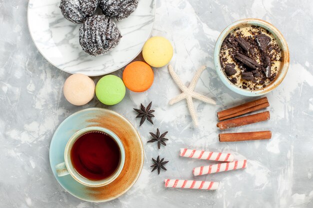 Bovenaanzicht kopje thee met kaneel macarons en chocoladetaart op wit bureau bakken cake koekje suiker zoete taart