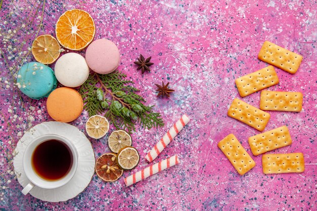 Bovenaanzicht kopje thee met kleurrijke Franse macarons en crackers op roze muur cake koekje suiker zoete taart thee koekje