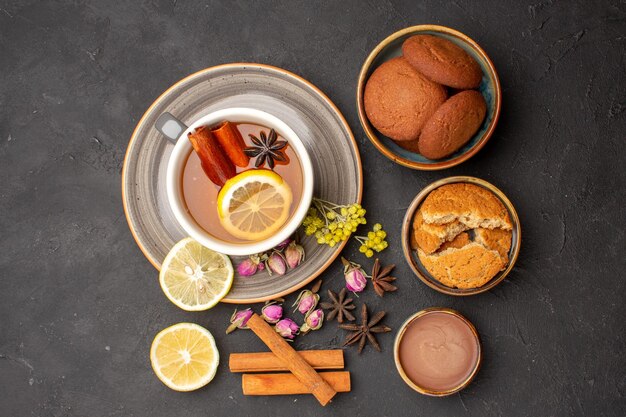 Bovenaanzicht kopje thee met koekjes en schijfjes citroen op het donkere oppervlak thee suiker fruitkoekje zoet koekje