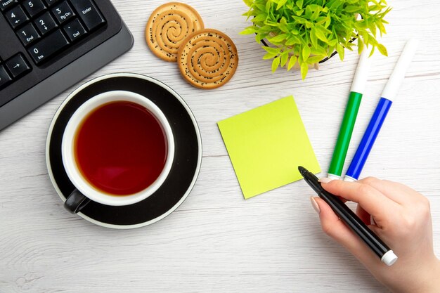 Bovenaanzicht kopje thee met schriftelijke motivatie notities op een witte achtergrond zoete zakelijke toetsenbord vrouwelijke pauze baan werknemer office